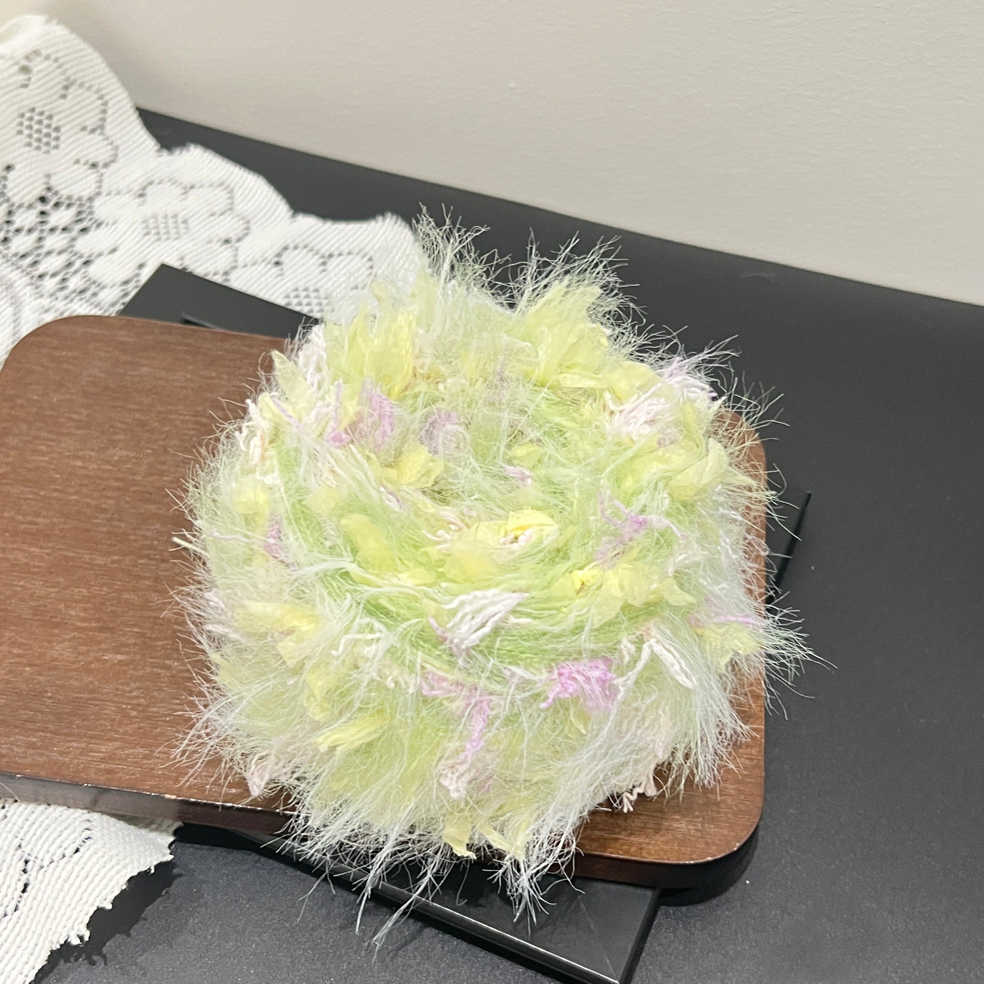 Center overhead view multi-tone pastel floral yarn cake showing airy fuzzy layered fiber texture