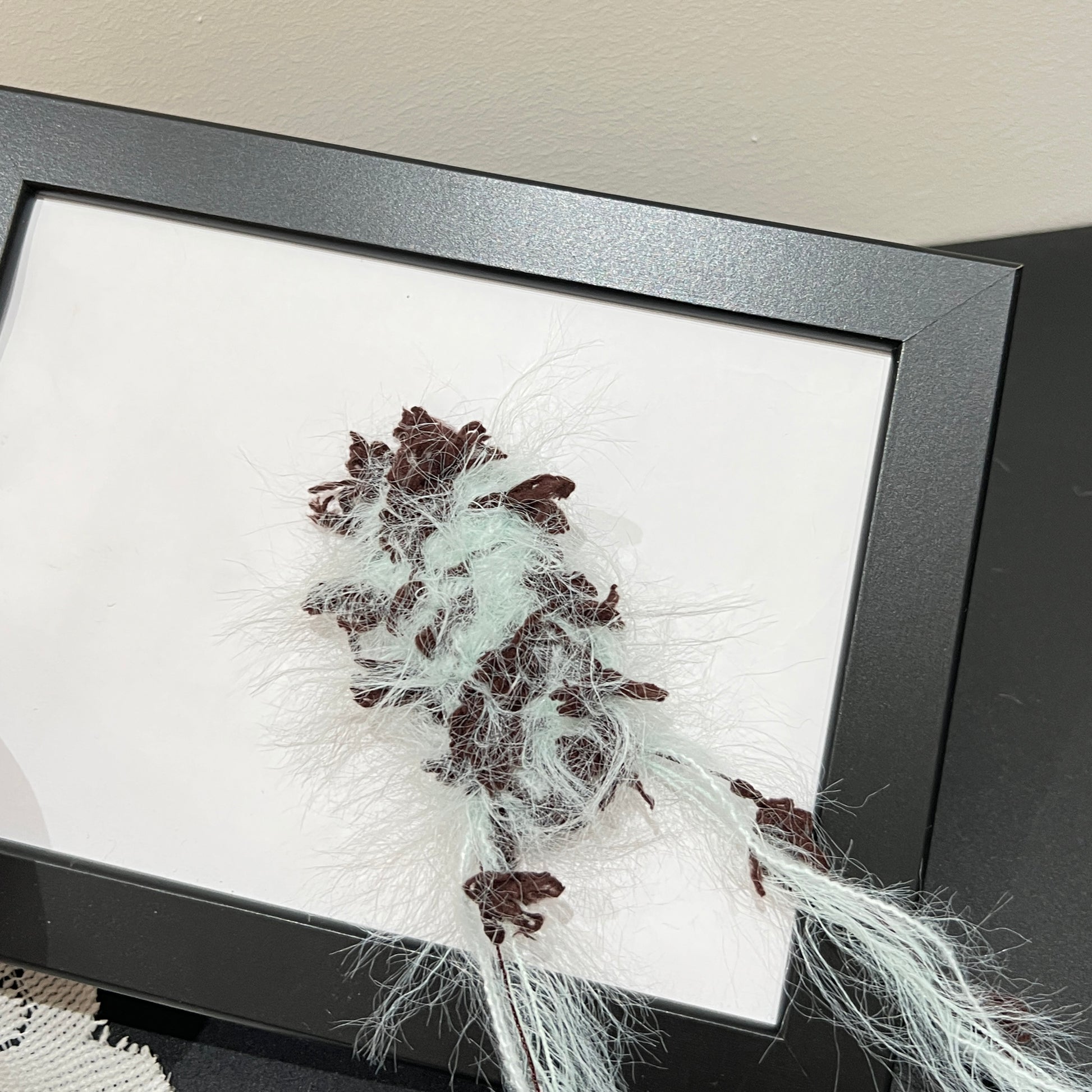 Close-up macro detail of pastel mint brown petal layered multi-strand blended fiber texture on black display frame