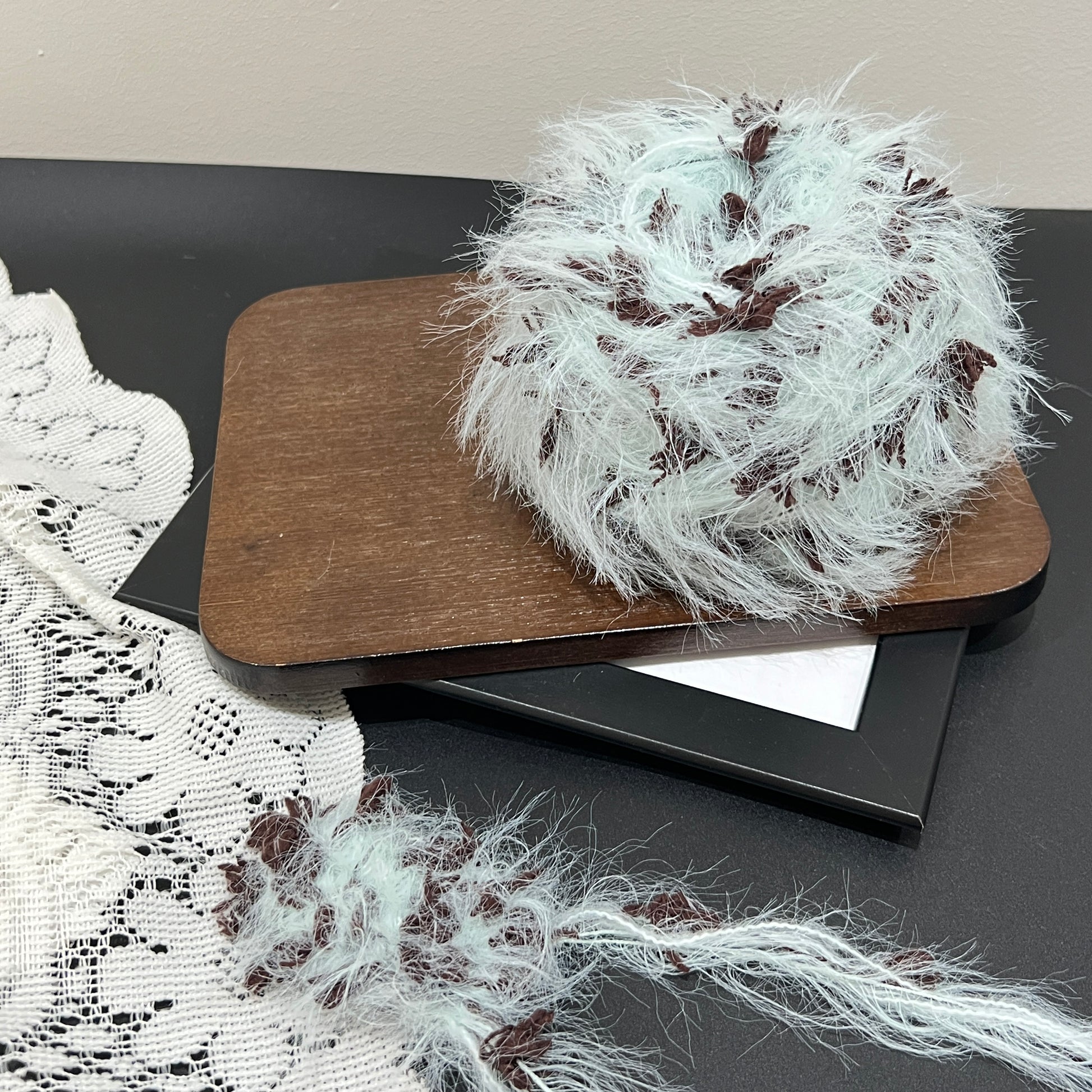 Front overhead round view pastel mint brown layered floral hand-blended cake yarn on wooden tray