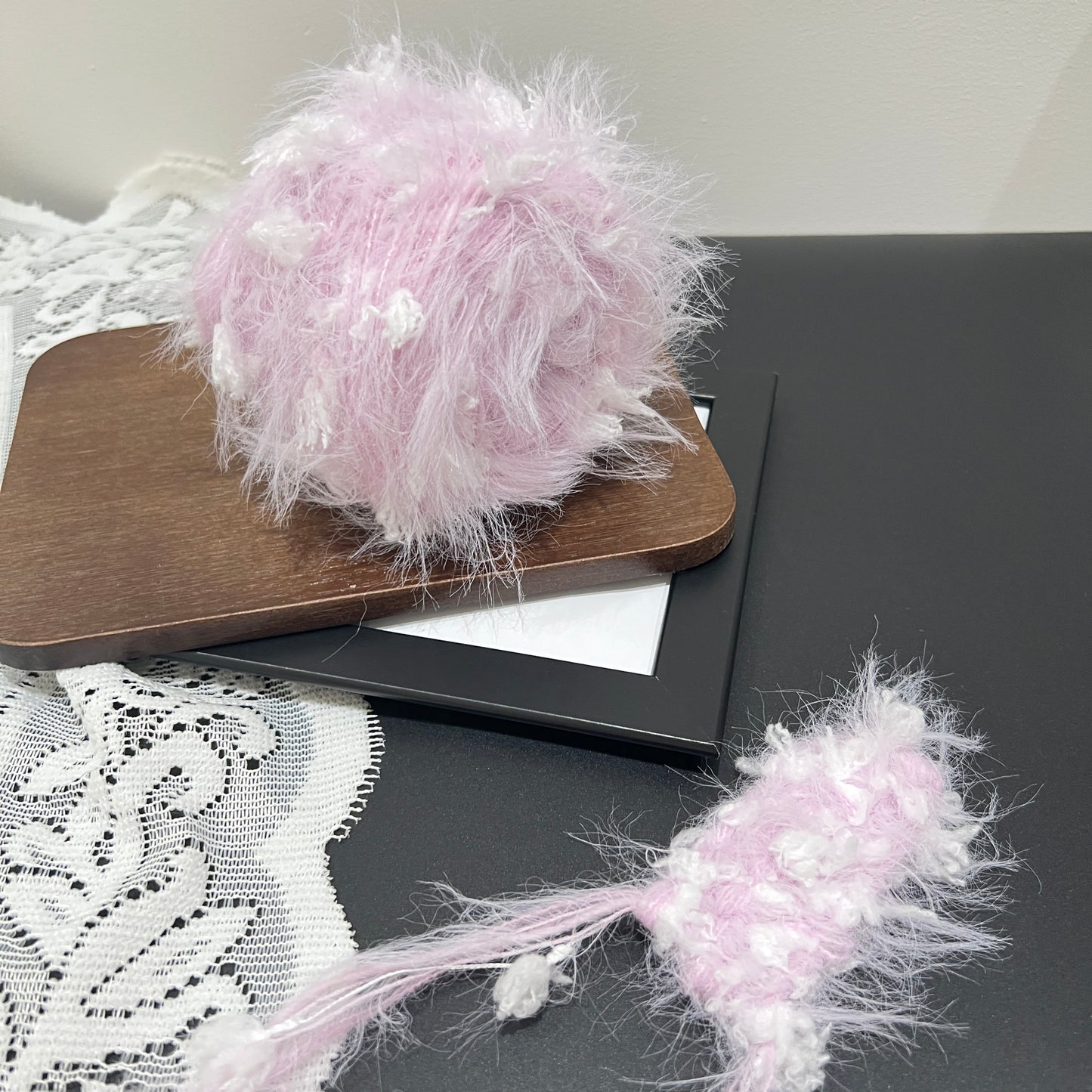 Pastel purple floral hand-blended yarn cake matched with fiber swatch beside white lace fabric decor