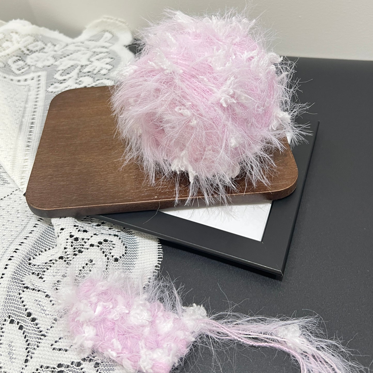 Pastel purple white floral multi-strand hand-blended cake yarn placed on wooden board with white lace fabric backdrop