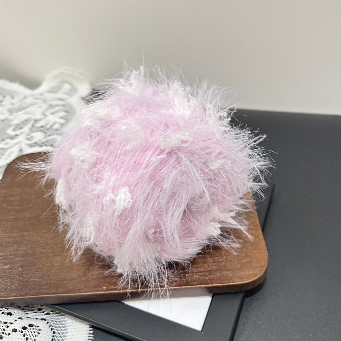 Overhead round shot pastel purple white layered floral hand-blended cake yarn on wooden tray