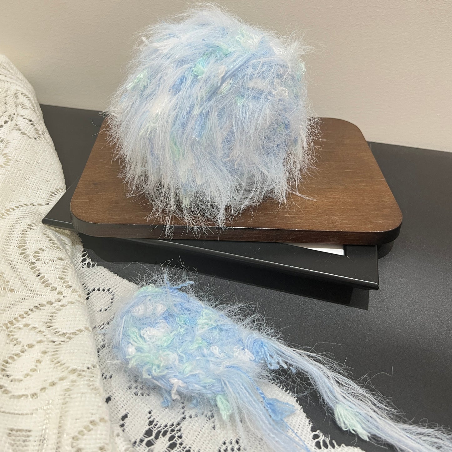 Front overhead spherical view pastel sky mint layered floral hand-blended yarn cake on wooden tray