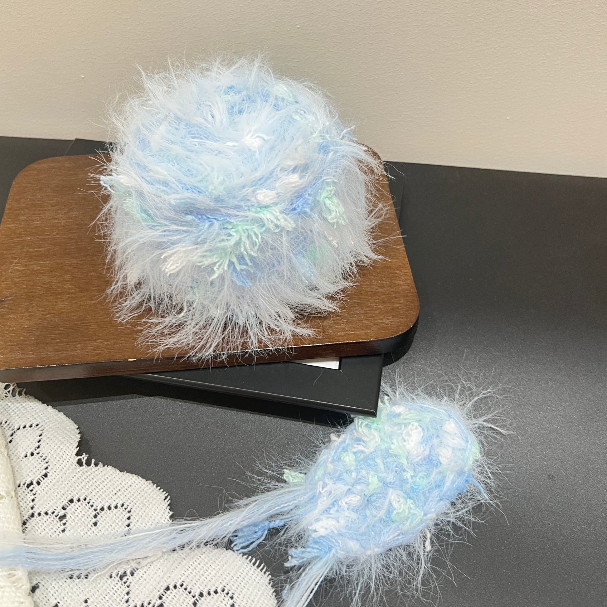 Pastel sky blue mint floral multi-strand hand-blended cake yarn placed on wooden board against neutral wall backdrop