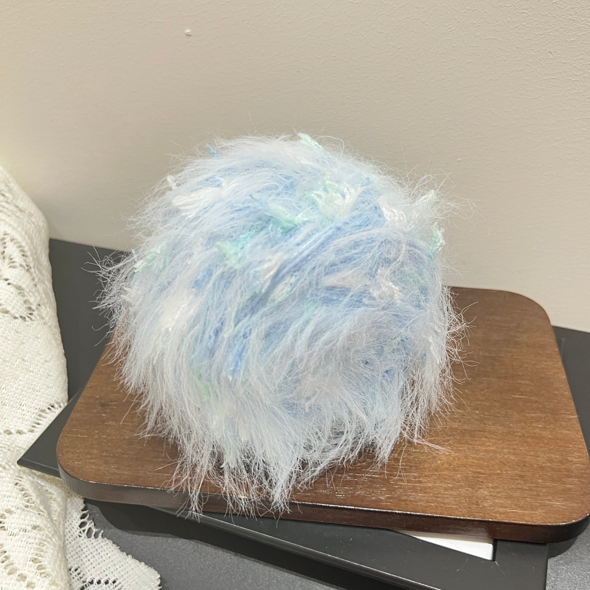 Top overhead full shot pastel sky mint floral yarn ball showing airy layered fuzzy fiber texture