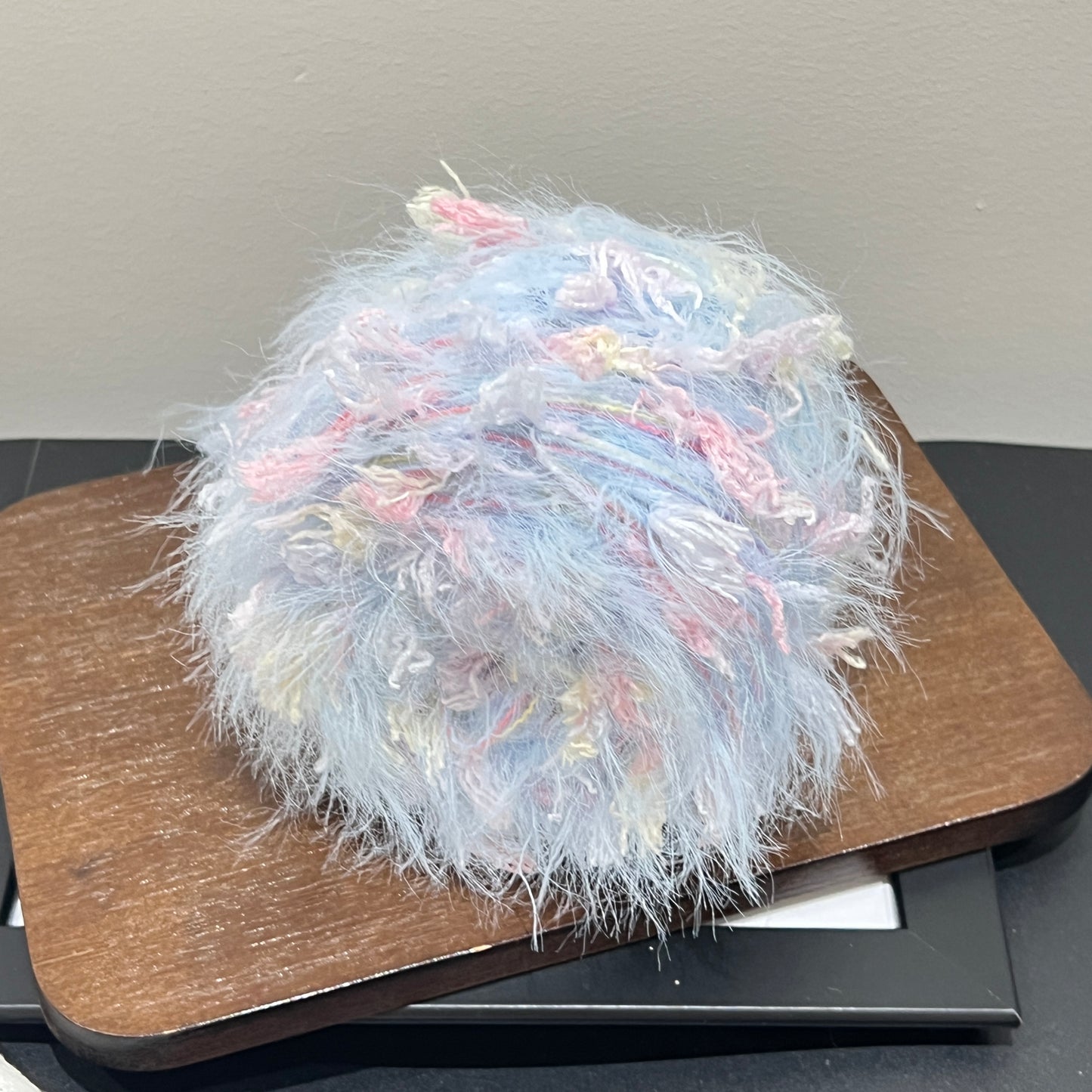 Center overhead view multi-pastel floral yarn cake showing airy fuzzy layered fiber texture
