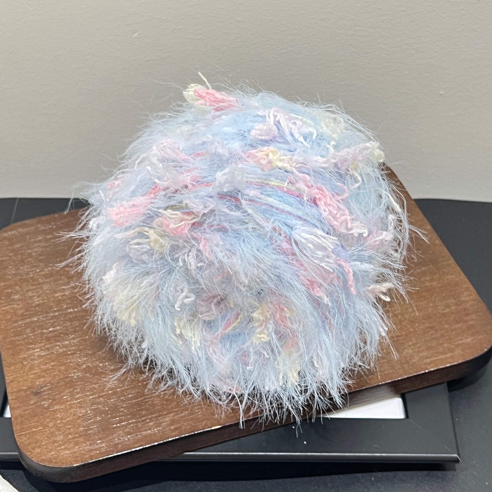 Center overhead view multi-pastel floral yarn cake showing airy fuzzy layered fiber texture