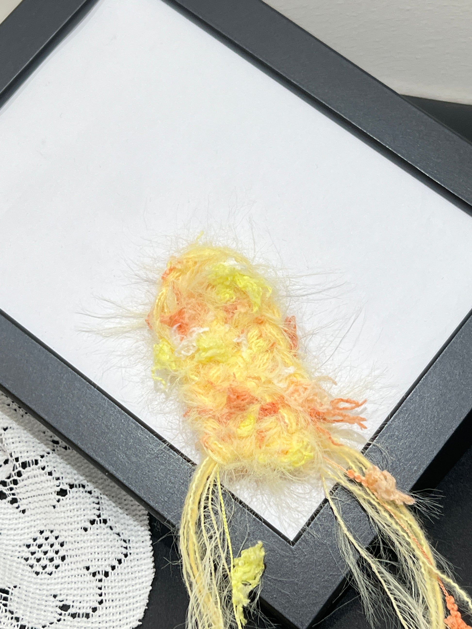 Close-up detail of pastel sunset yellow orange petal layered multi-strand blended fiber sample on black display frame