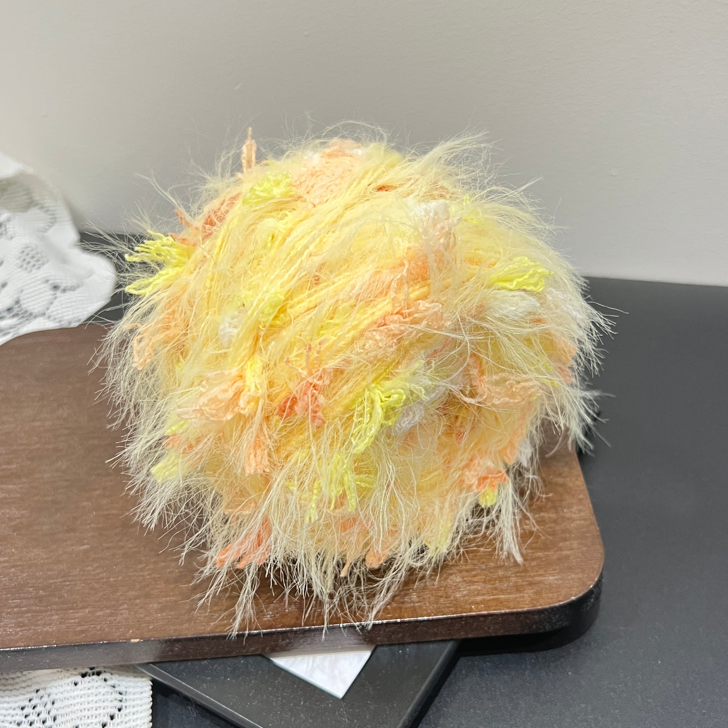Side angle shot pastel yellow orange layered floral hand-blended cake yarn with soft multi-strand texture