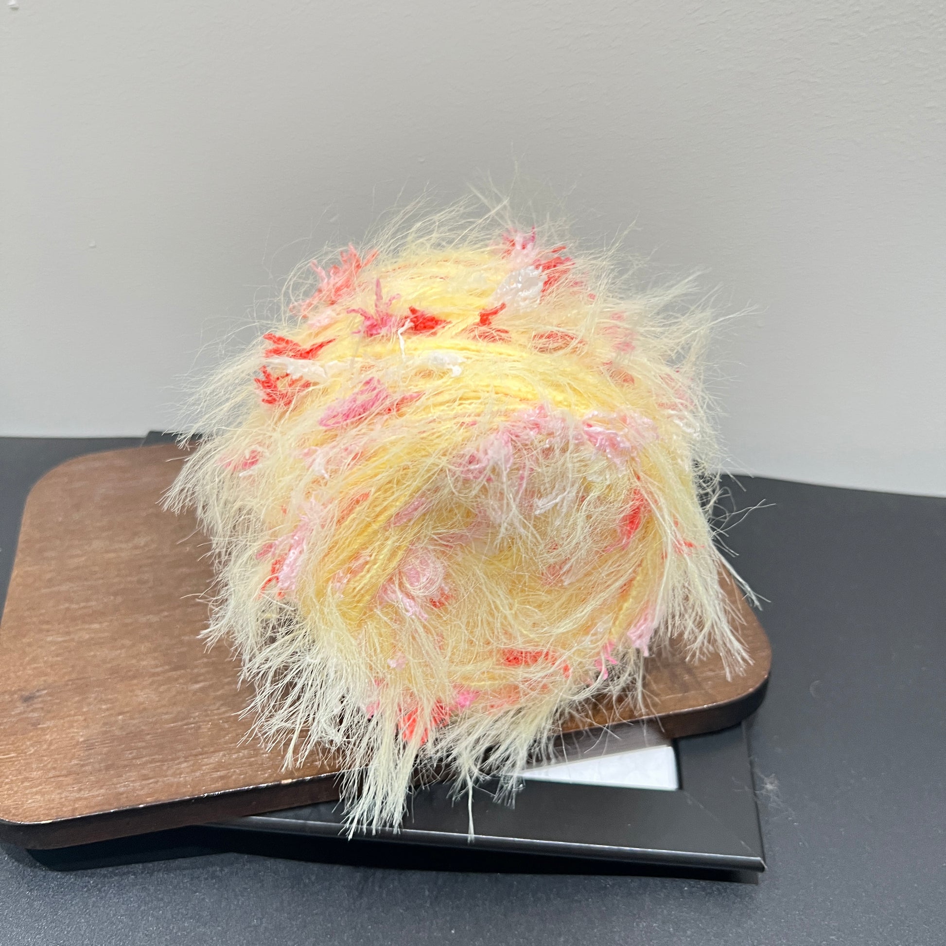 Front overhead spherical view pastel yellow layered floral hand-blended yarn ball with blush & scarlet petal accents