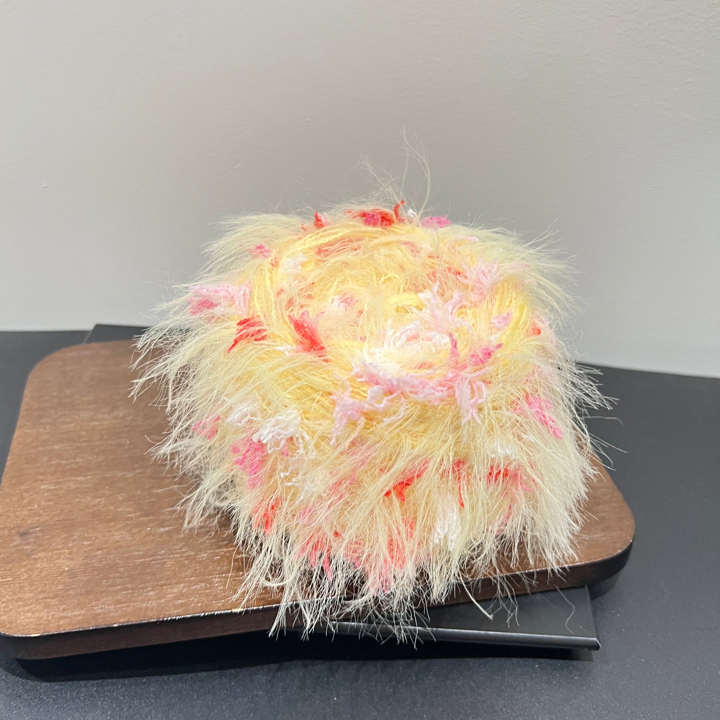Side angle shot pale yellow base artisan blend yarn scattered with blush pink and scarlet red petal fiber details