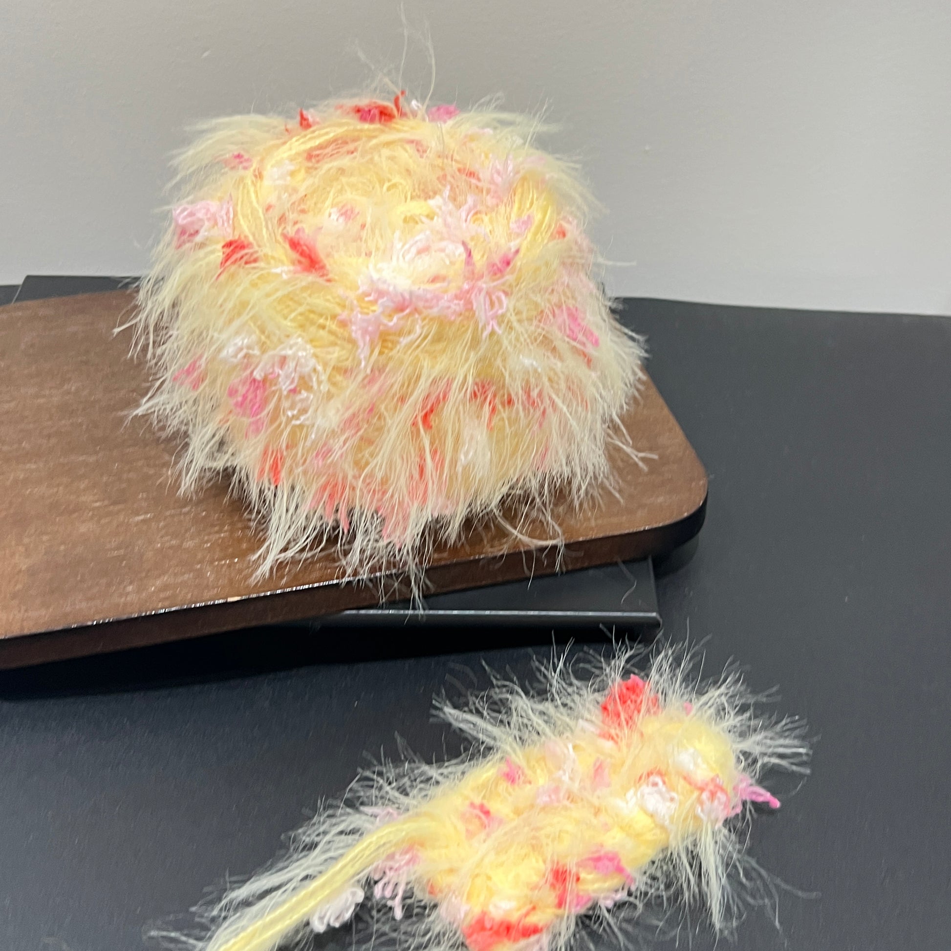 Layout shot of yellow blush red yarn cake and matching fiber swatch beside hollow white lace fabric