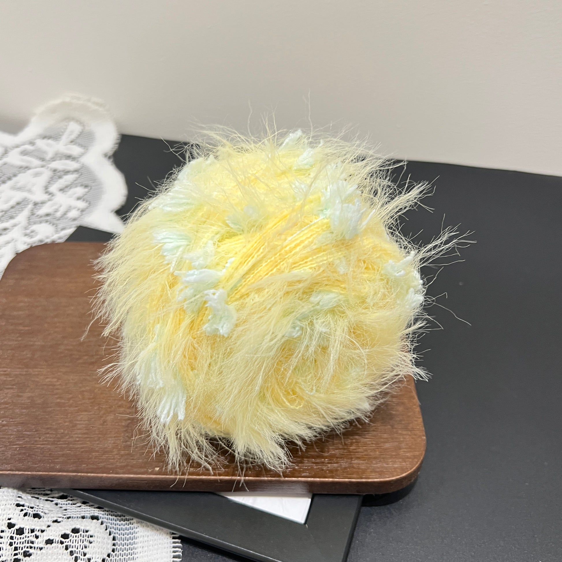 Top overhead view pastel yellow mint floral hand-blended cake yarn with layered fiber texture