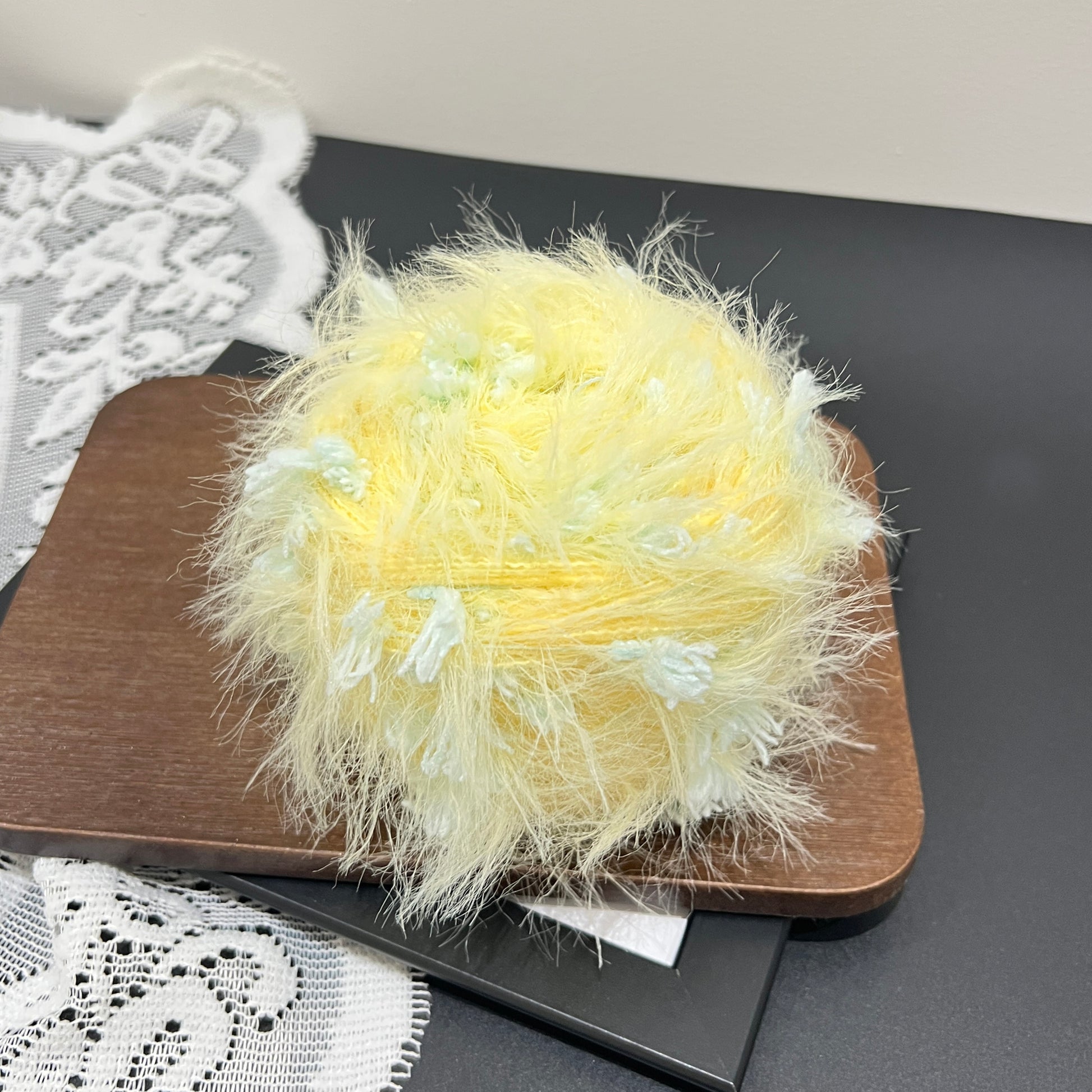 Side angle shot pastel yellow mint floral multi-strand blended yarn cake with petal fiber accents