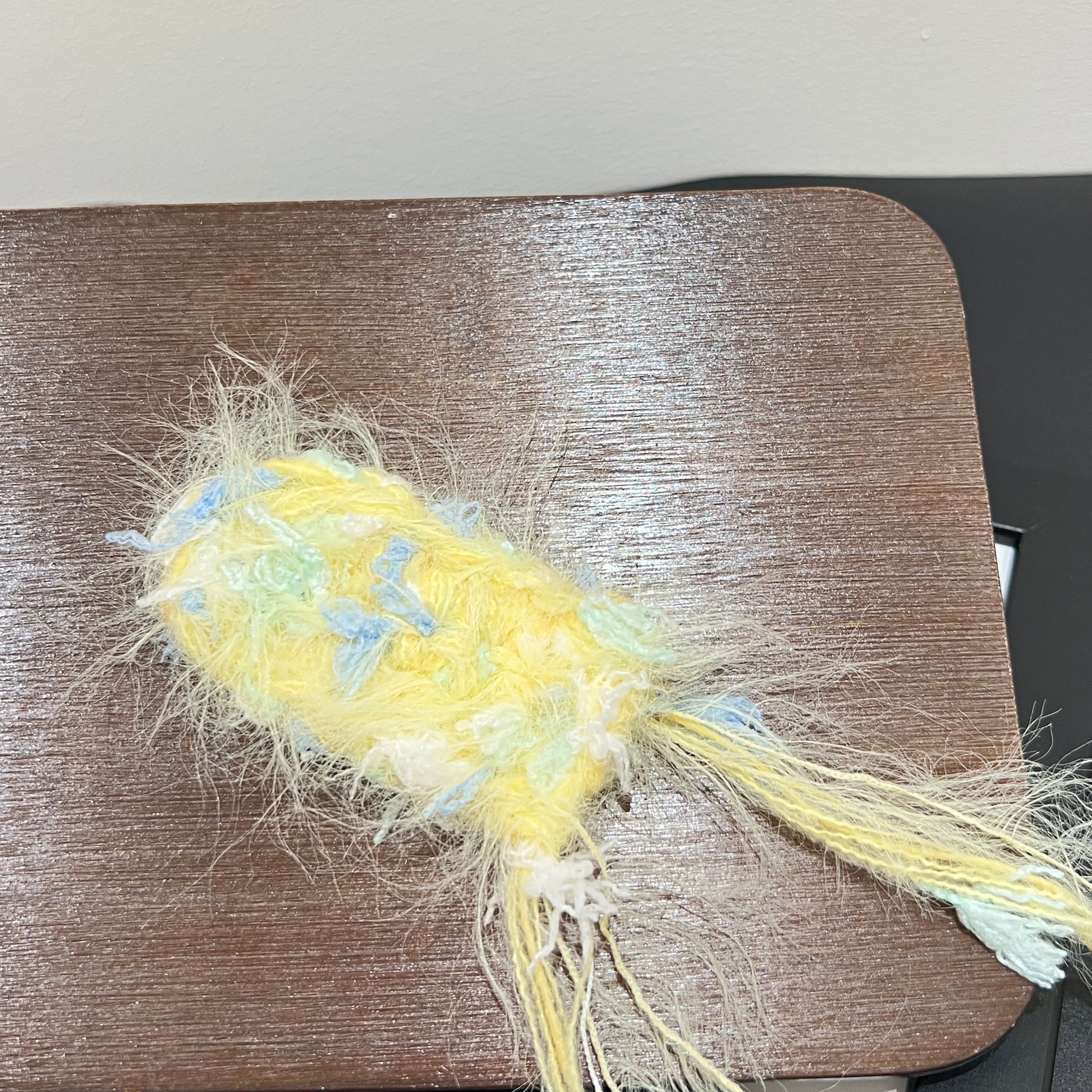 Close-up macro detail of pastel yellow sky mint petal layered multi-strand blended fiber mounted on wooden display board