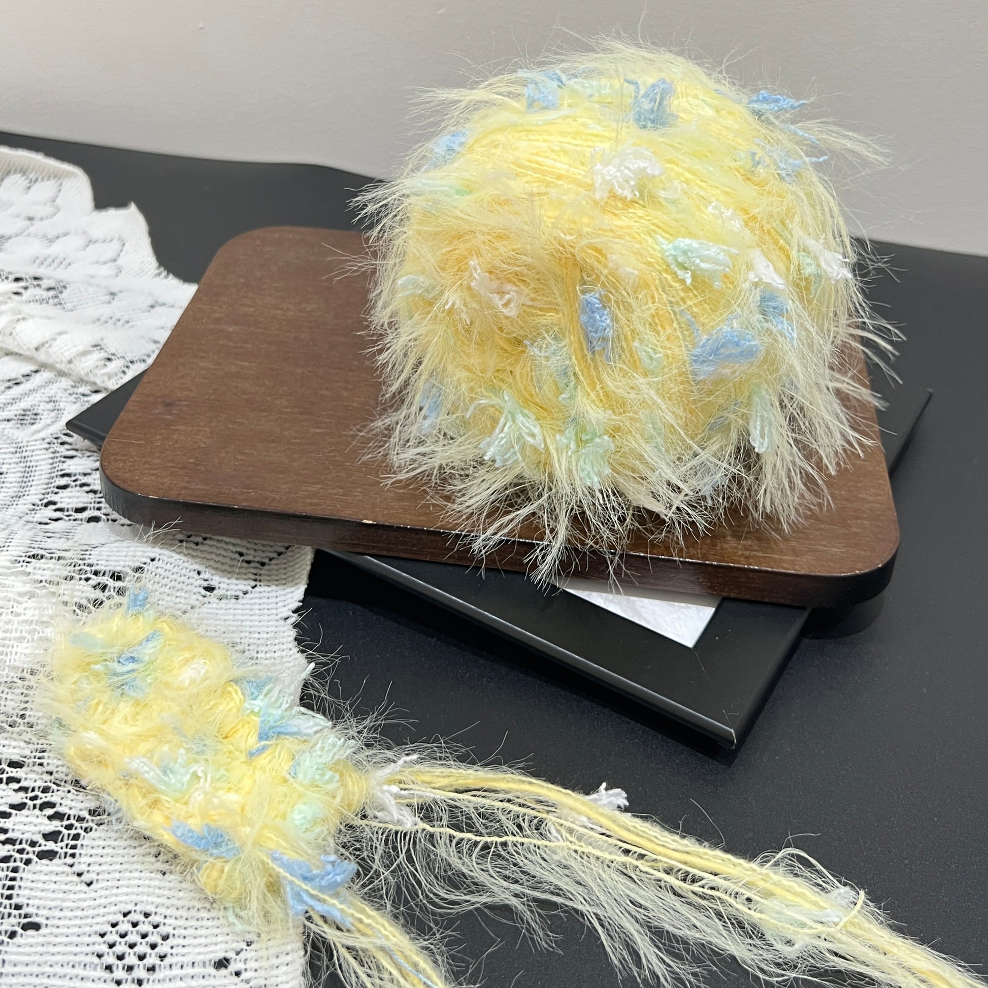 Front overhead spherical view pastel yellow layered floral hand-blended yarn cake with sky blue & mint petal accents