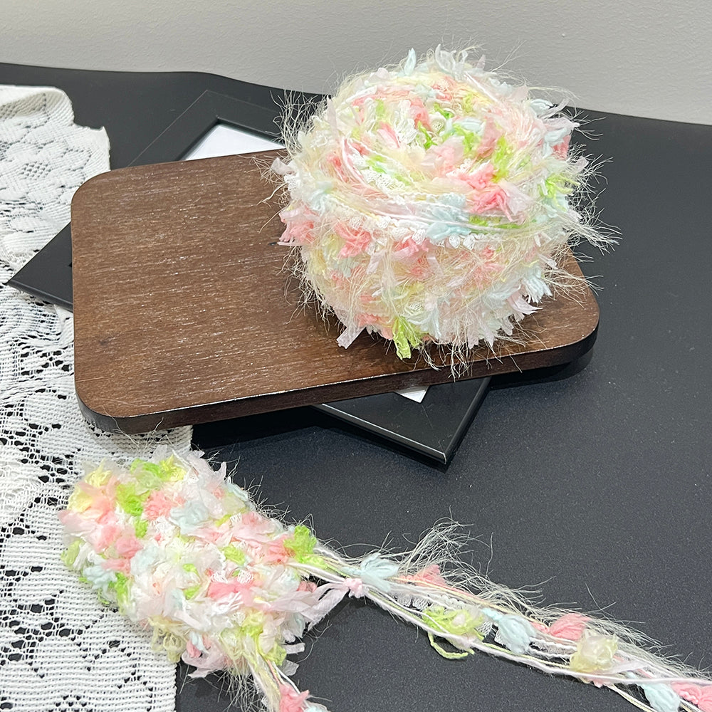 Spring pastel floral cake yarn laid on wooden tray with lace backdrop, artisan blended fancy yarn