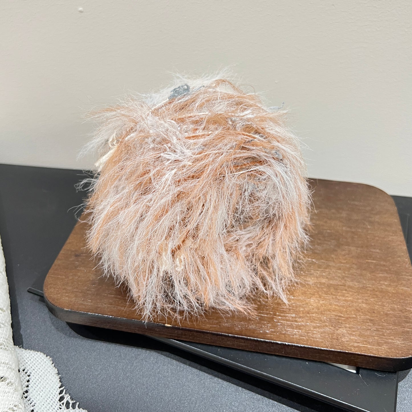 Wide layout shot yarn cake + long tassel fiber swatch, hollow white lace fabric on dark tabletop