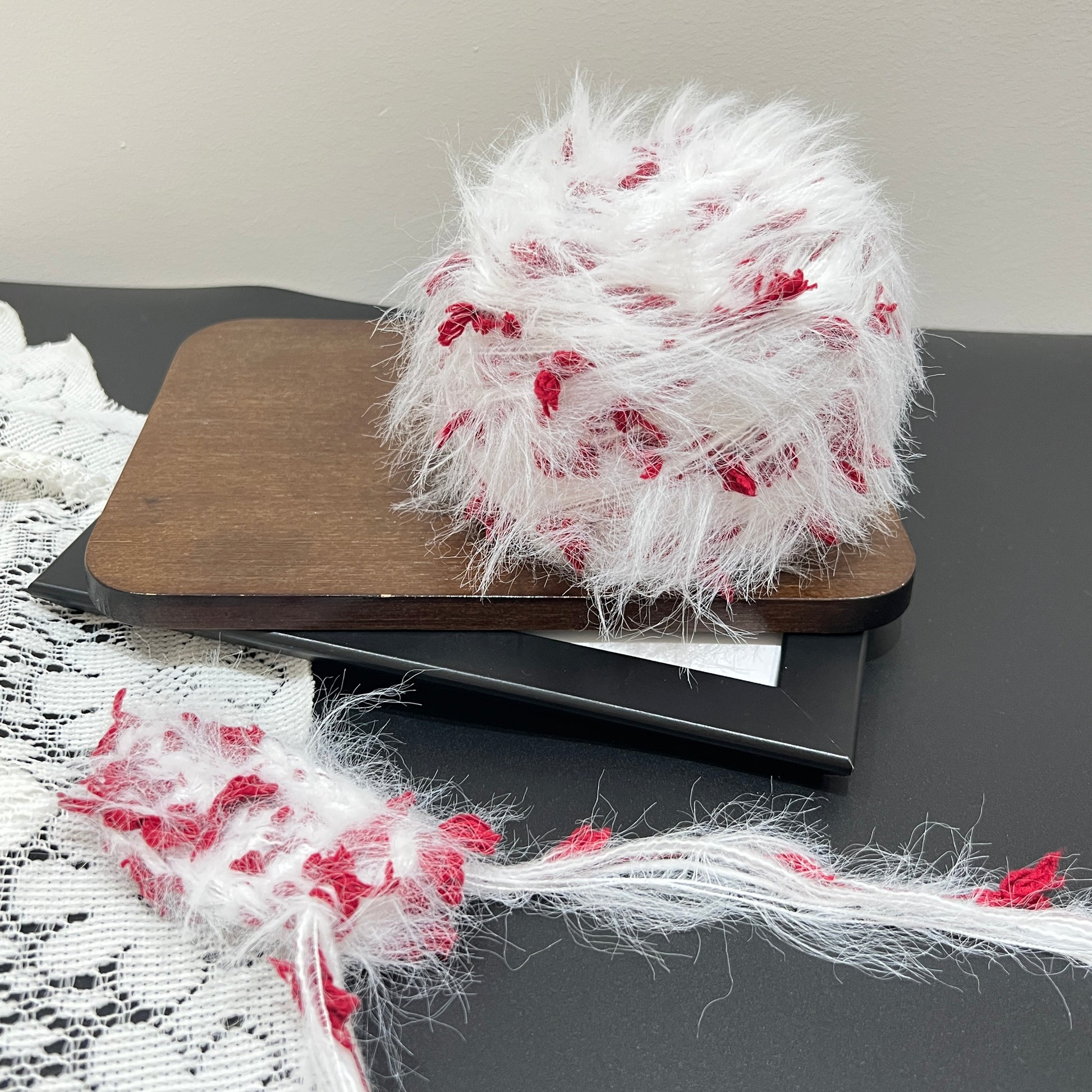 Front overhead spherical view white crimson layered floral hand-blended yarn cake on wooden tray