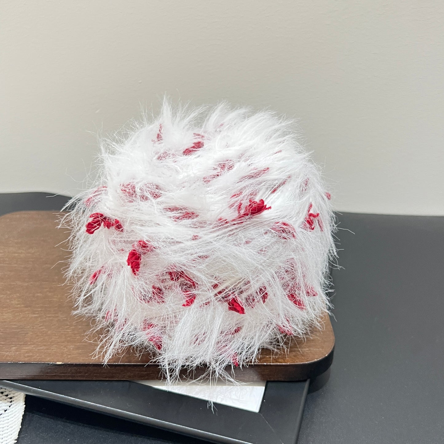 Complete set display yarn ball + fiber swatch with white lace decor on dark flat surface